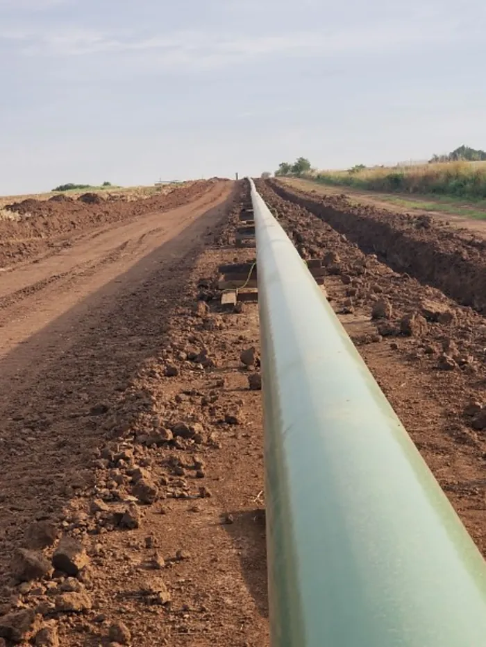 Coated pipe strung along an open ditch